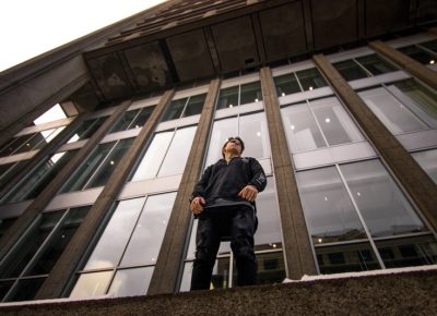 A boy standing in front of a large glass wall.