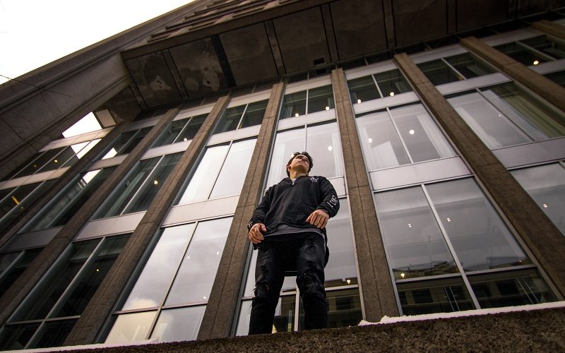 A boy standing in front of a large glass wall.